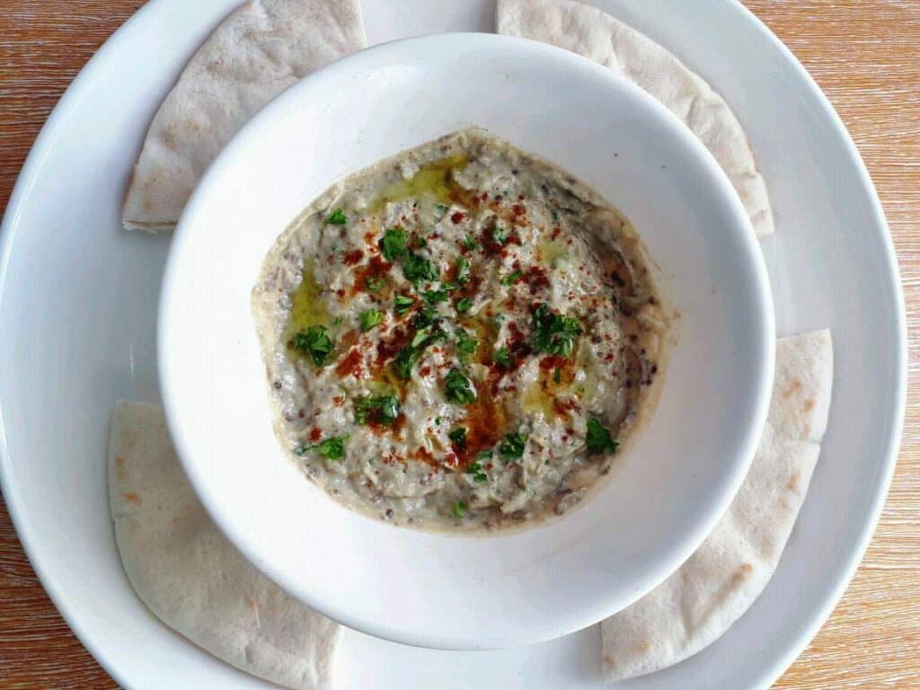 Roasted Aubergine Dip (Baba Ganoush) serve with 4 pieces of flatbread in a plate