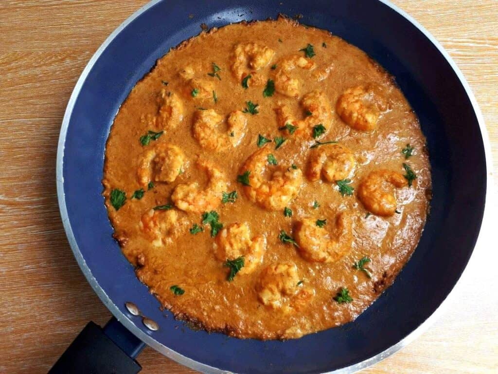 Creamy and Spicy Prawn Masala Recipe garnish with chopped coriander in a pan.