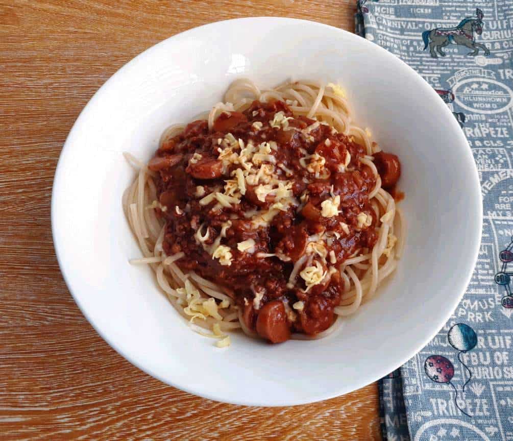 Filipino style spaghetti with red sauce and topping of grated cheese