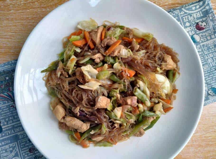 Pancit Sotanghon Guisado with vermicelli noodle, chicken breast, julienne carrots, string beans and cabbage in a plate