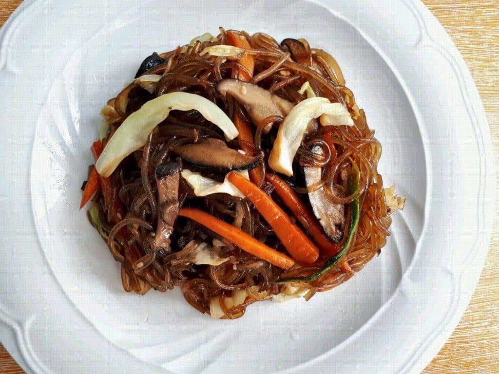 Vegan Japchae Korean Glass Noodles with cabbage, carrots and mushroom in a plate