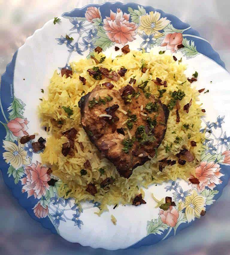 Fish Machboos mixed with turmeric basmati rice, boneless spanish mackerel fish. and garnished with fried brown onion and parsley.