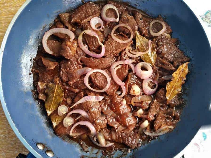 Filipino Beef Steak Bistek Tagalog garnished with Onion ring in a pan.