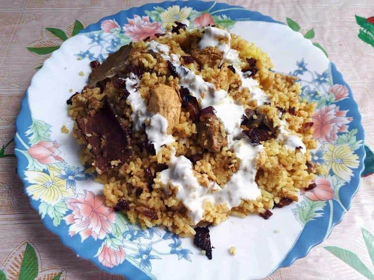 Arabic Biryani Recipe mixed with chicken, yellow turmeric rice and drizzle with yogurt garlic sauce in a plate.