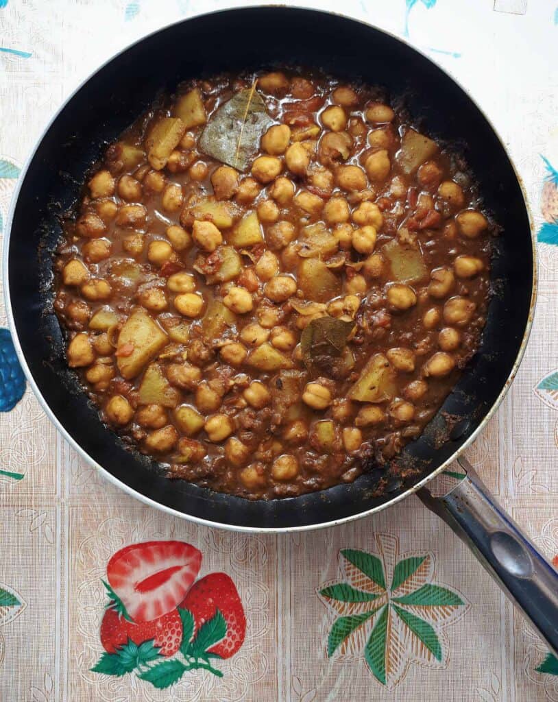 A potato and chickpeas curry recipe Aloo Chole with bay leaves, tomato sauces and other spices & herbs serve in a pan