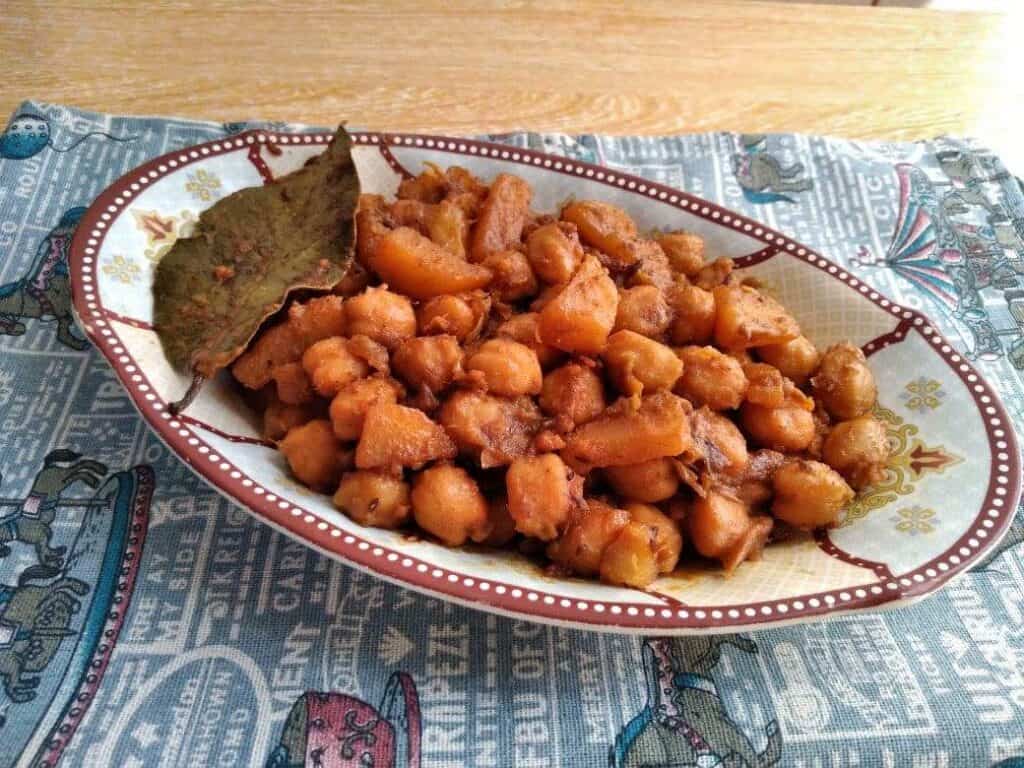 Aloo Chole mixed with chickpeas and potatoes with spices and bay leaves served in a plate