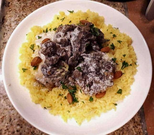 Jordanian Mansaf served with lamb and yellow rice and garnished with fried almonds and chopped parsley