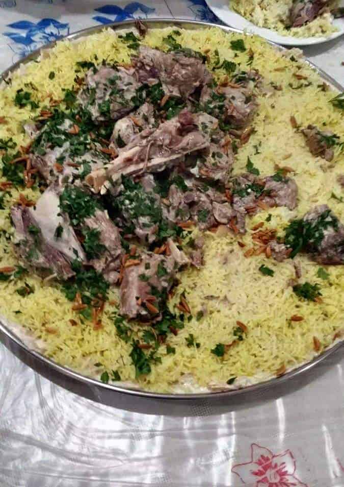 Jordanian Mansaf served with lamb and yellow rice and garnished with fried pine nuts and chopped parsley