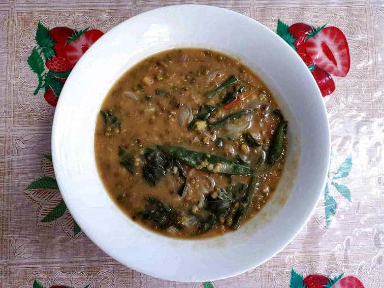 A filipino mung bean soup Ginisang Monggo mixed with spinach and green beans served in a plate bowl.