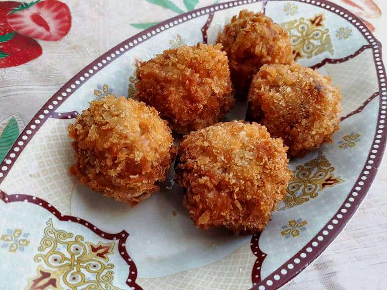 a deep fried Shrimp Croquettes in a ball shaped serve in a plate