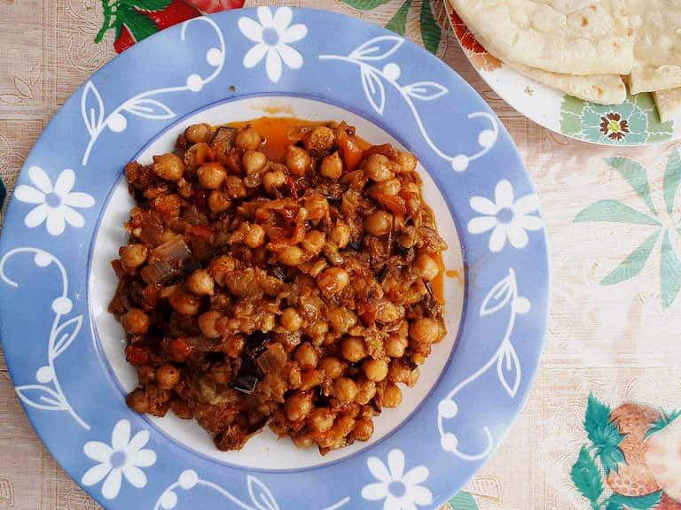 Lebanese Moussaka or Maghmour vegan eggplant recipe mixed with chickpeas, onion, garlic, and tomatoes with pita bread serve on a plate.