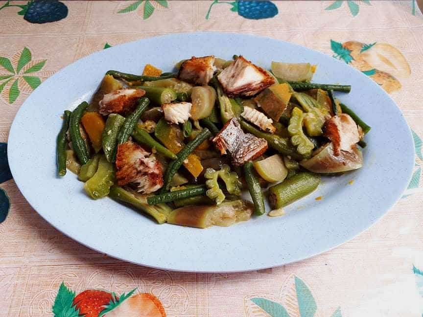 Pinakbet Ilocano recipe mixed with okra, bitter melon, eggplant, green beans and squash, chopped boneless fried fish on a plate