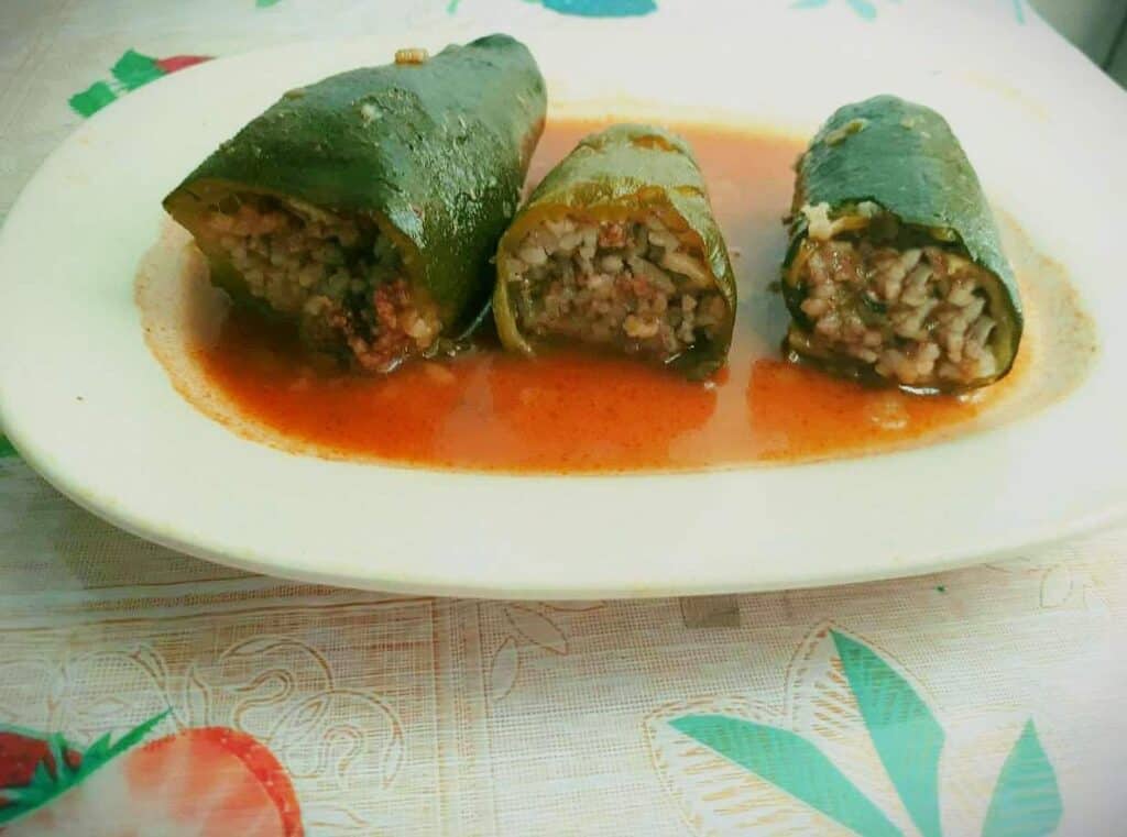 A Sliced Lebanese stuffed Zucchini called Kousa Mahshi with rice inside and tomato sauce on a plate