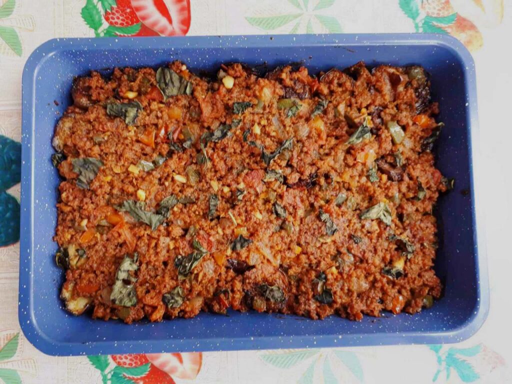 A Turkish moussaka dish mixed with ground beef, tomato sauce, eggplant and chopped basil leaves on a baking tray