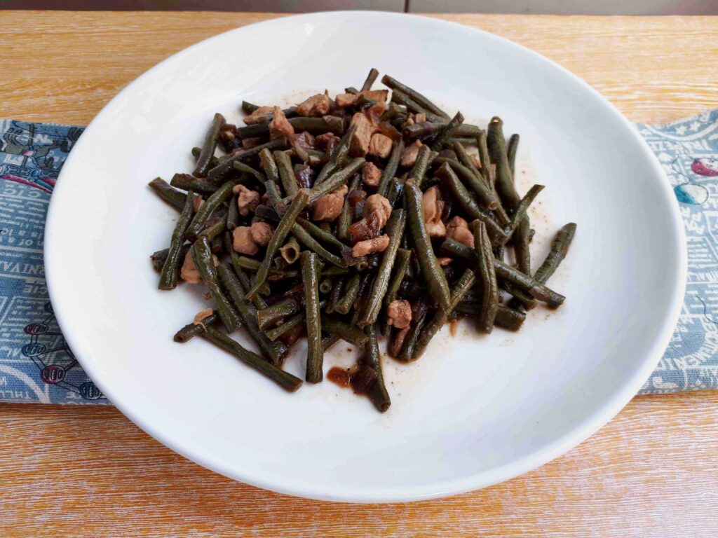 Adobong Sitaw green bean recipe mixed with chopped boneless chicken breast on a plate