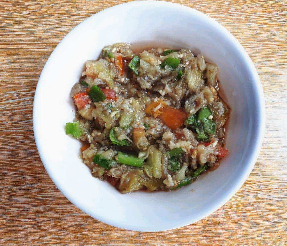 Filipino eggplant salad called Ensaladang mixed with mashed eggplant, chopped tomatoes & spring onion serve on a plate bowl.