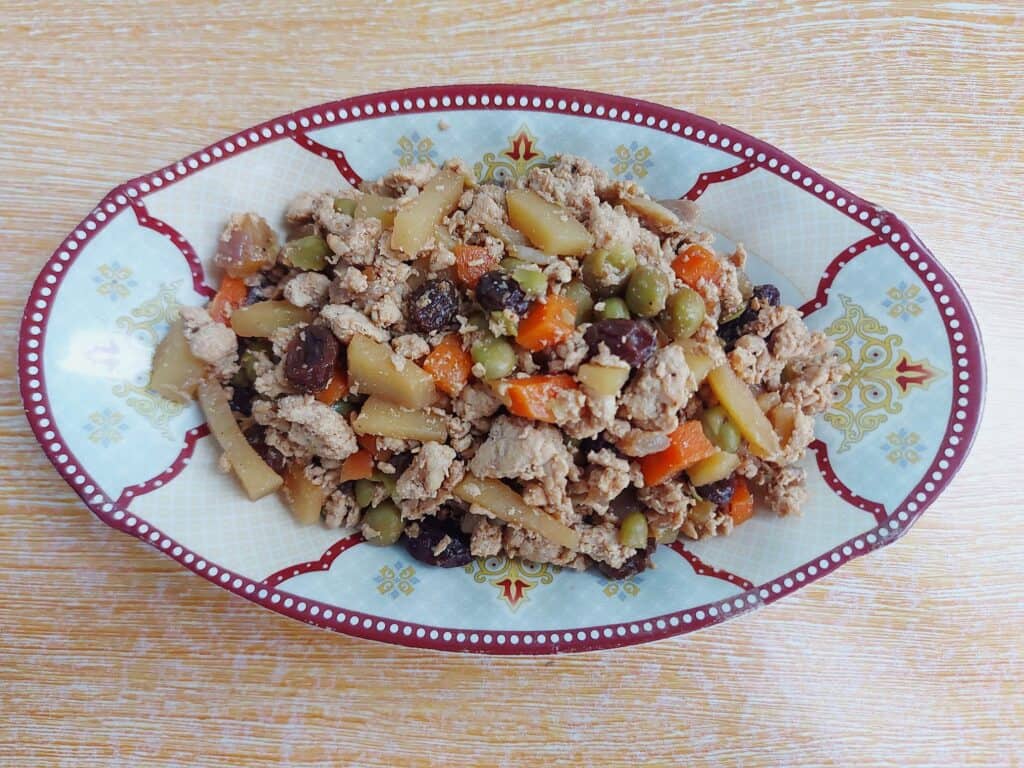 A filipino ground meat dish Chicken giniling mixed with raisins, chickpeas, potatoes and carrots serve in a plate