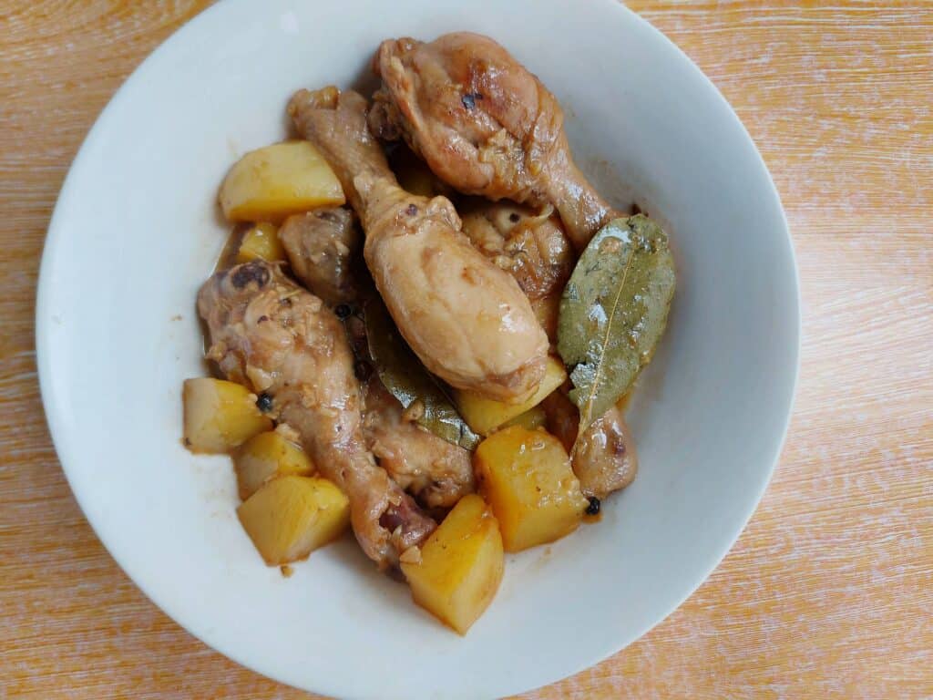 A filipino chicken adobo with potatoes, bay leaves, peppercorn served on a plate bowl