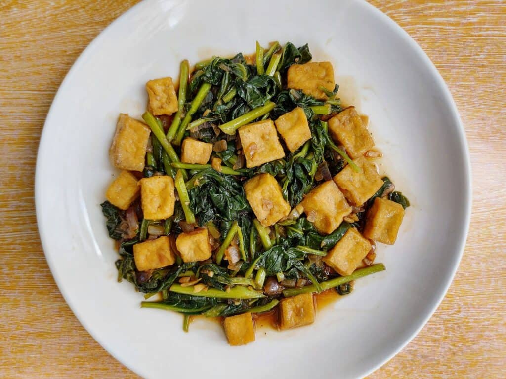 A Filipino vegetable recipe Adobong Kangkong with Tofu served on a plate