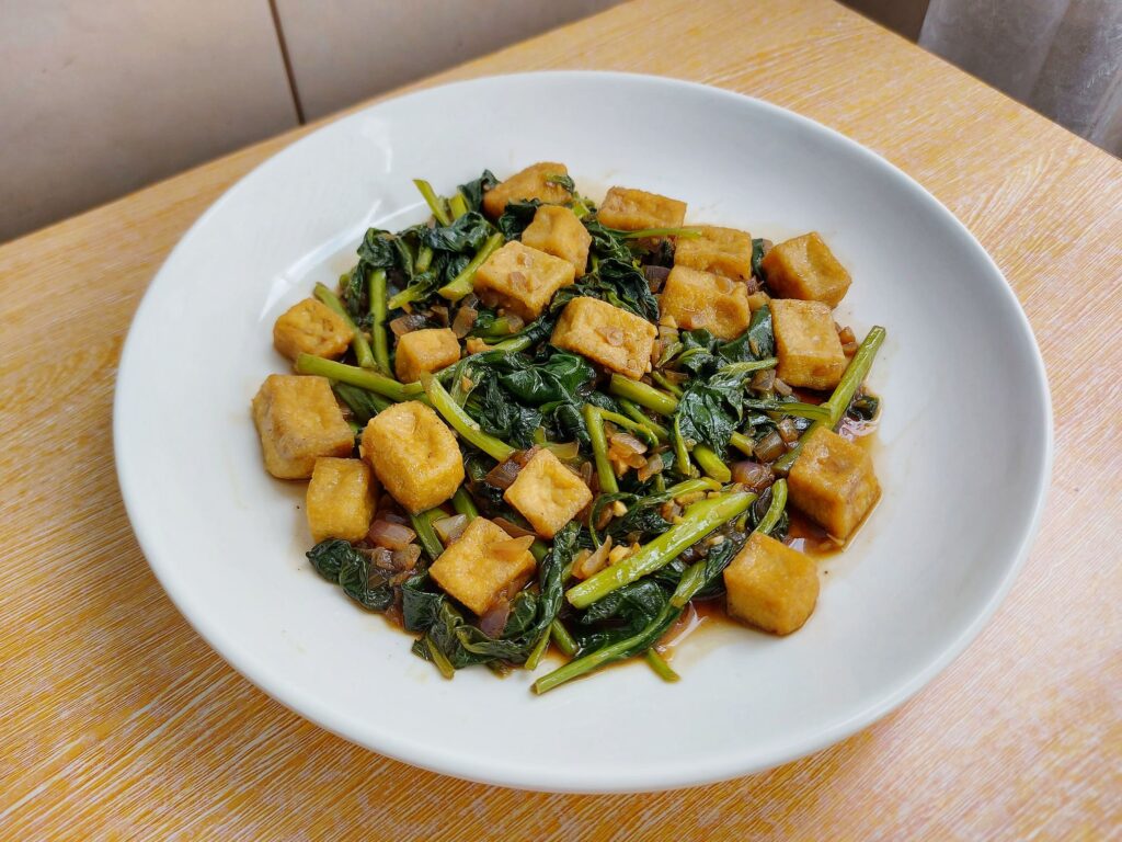 A Filipino vegetable recipe Adobong Kangkong with Tofu served on a plate