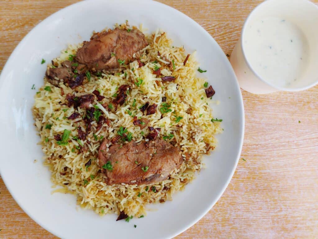 Chicken Arabic Biryani mixed with yellow rice garnished with chopped parsley serve with yogurt garlic sauce