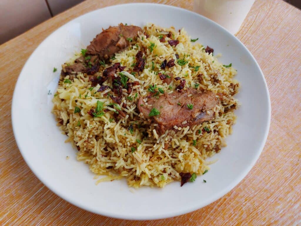 Chicken Arabic Biryani mixed with yellow rice garnished with chopped parsley serve on a plate