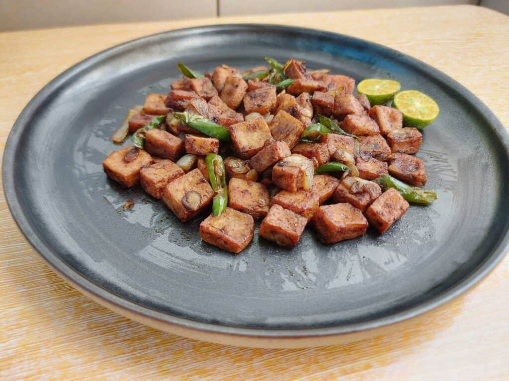 A filipino tofu sisig with green chilies and calamansi served on a plate 