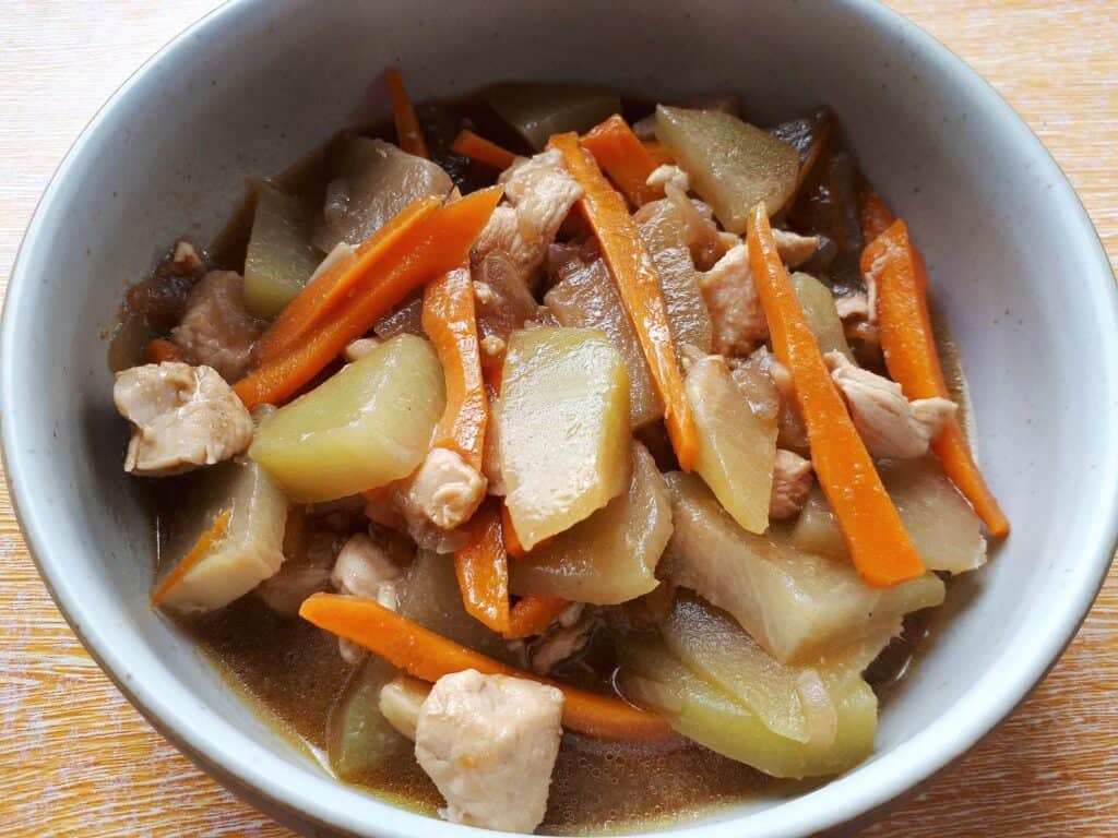 Filipino Chayote recipe Ginisang Sayote  with julienned carrot and chopped chicken breast served on a plate bowl