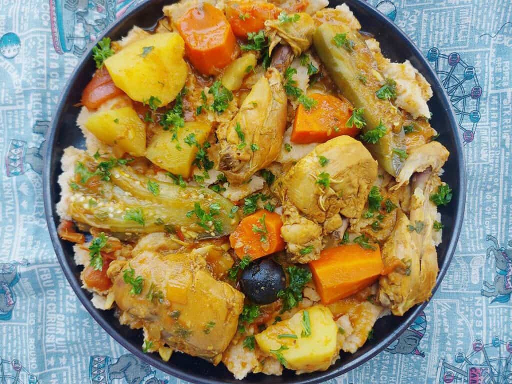 A Kuwaiti Gulf Arabic recipe Tashreeb that is mixed with chicken, potatoes, carrots and eggplant with pieces of flatbread under it and served on a plate.