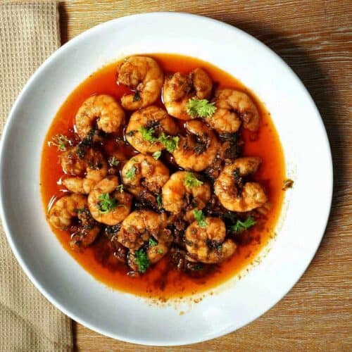 Spanish Garlic Prawns, also known as Gambas Al Ajillo, consist of garlics, prawns, garnished with parsley sauteed in olive oil with paprika served on a plate.