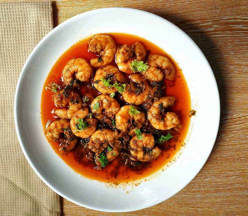 Spanish Garlic Prawns, also known as Gambas Al Ajillo, consist of garlics, prawns, garnished with parsley sauteed in olive oil with paprika served on a plate. 