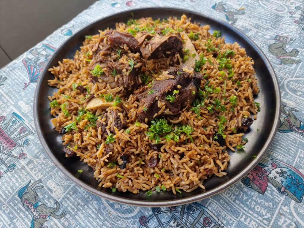 Beef Kabsa with aromatic long-grain rice with different spices garnished with chopped parsley served in a plate.