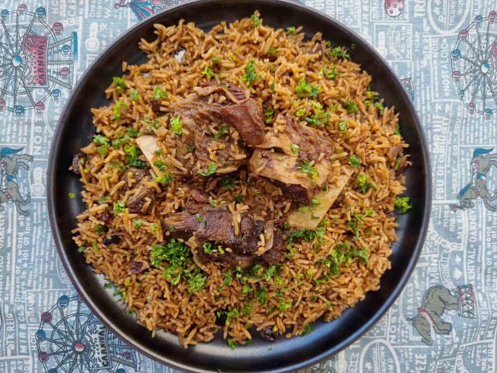 Beef Kabsa with aromatic long-grain rice with different spices garnished with chopped parsley served in a plate.