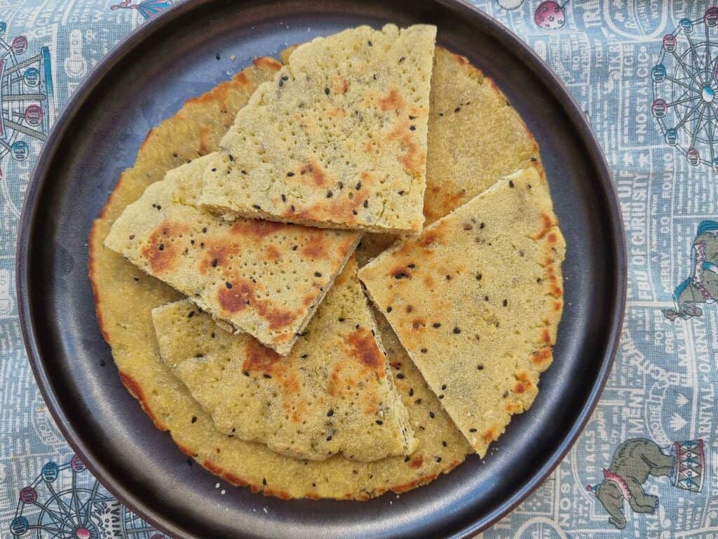 Algerian flatbread kesra with that is divided into 4 pieces served on a plate 