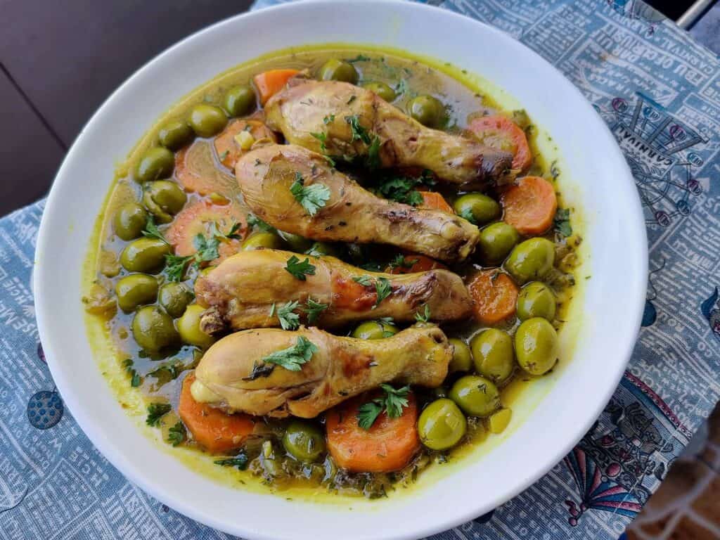 Tajine Zitoune: Algerian chicken stew with carrots, olives, and North African spices served on a plate.
