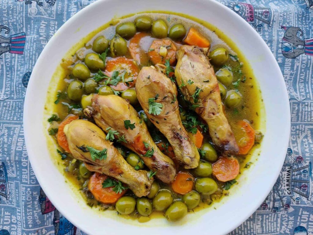 Tajine Zitoune: Algerian chicken stew with carrots, olives, and North African spices served on a plate.




