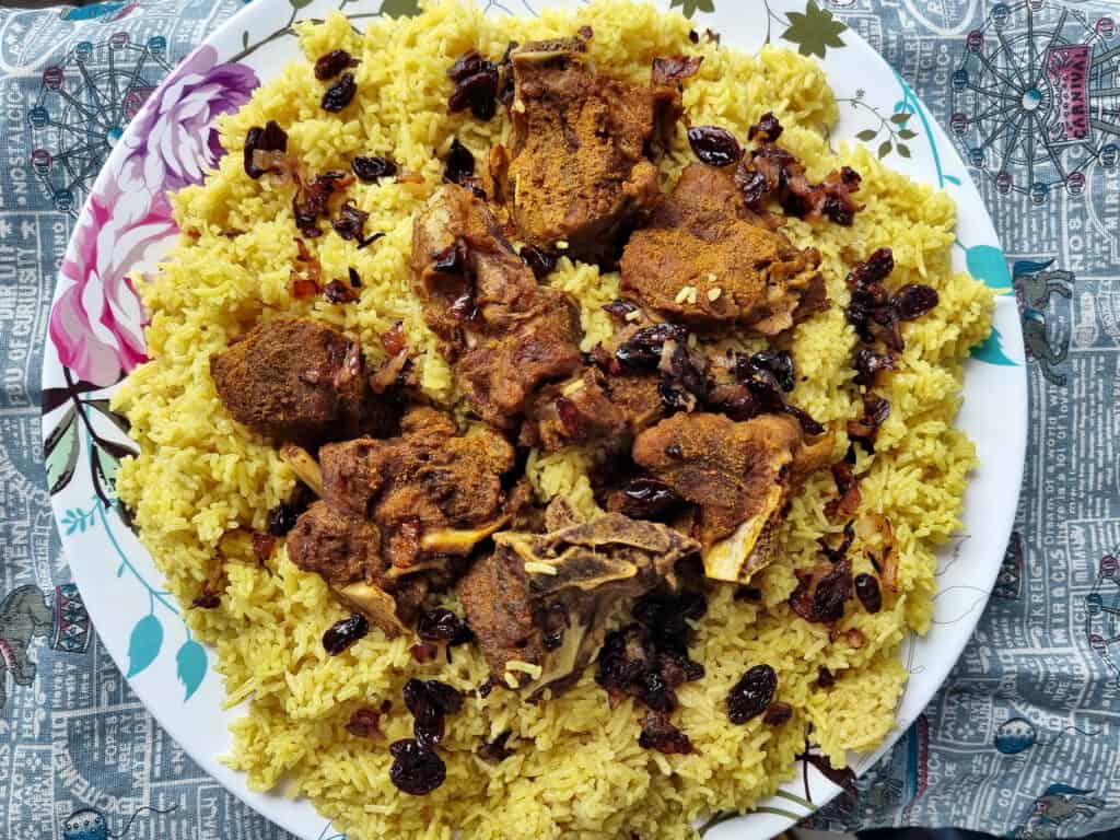 Beef Mandi recipe consists of beef, raisins, fried onion and basmati yellow rice served on a plate  