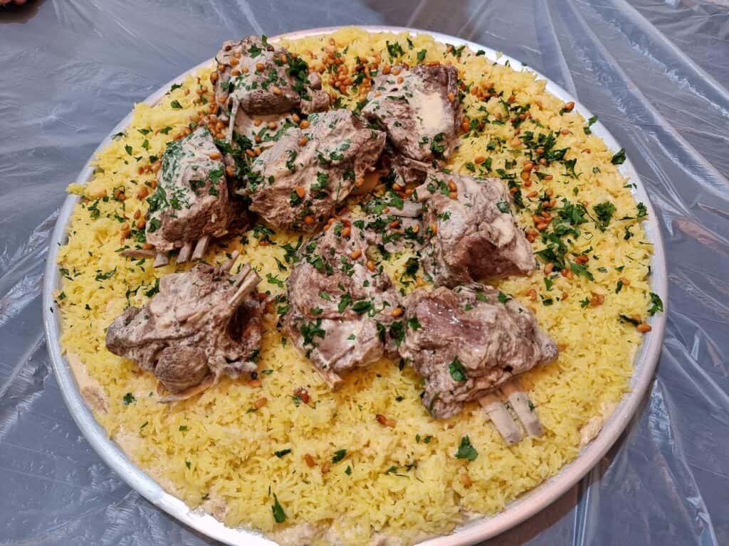 Jordanian Mansaf served with lamb and yellow rice and garnished with fried pine nuts and chopped parsley